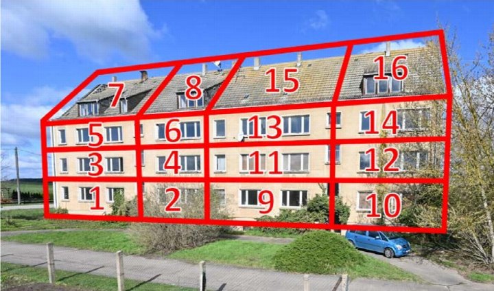 Außenansicht eines Mehrfamilienhauses in Trossin, Kirchgasse 6A, mit nummerierten Wohnungen und Dachgauben unter blauem Himmel