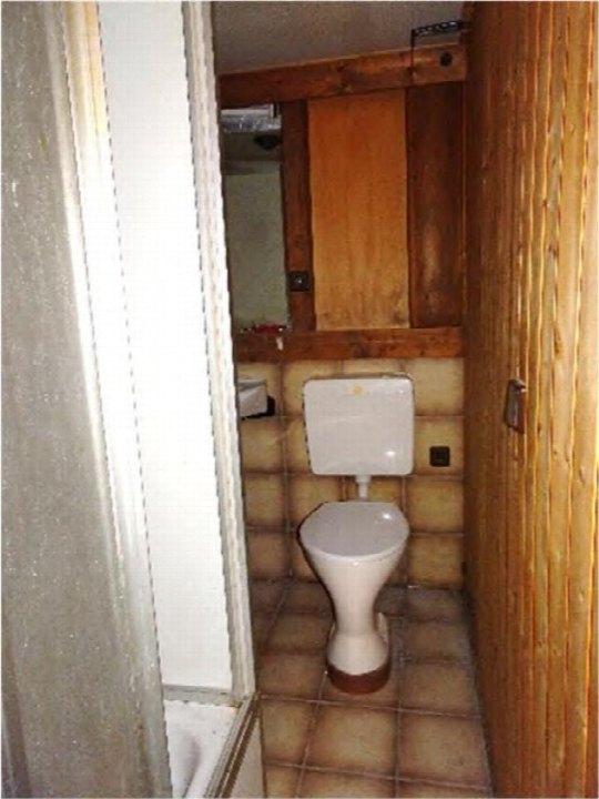 Kleiner Badezimmerbereich mit Toilette, Fliesenboden und Holzwänden im Hobbyraum 64, München