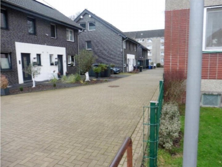 Seitenansicht einer Reihenhäuserzeile mit Pflasterweg, Grünanlagen und Eingängen in Gladbeck, Aldiekstraße 6 D