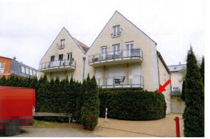 Seitenansicht eines Mehrfamilienhauses in Trassenheide, Strandstraße 21, mit Balkonen und Hecken im Vordergrund