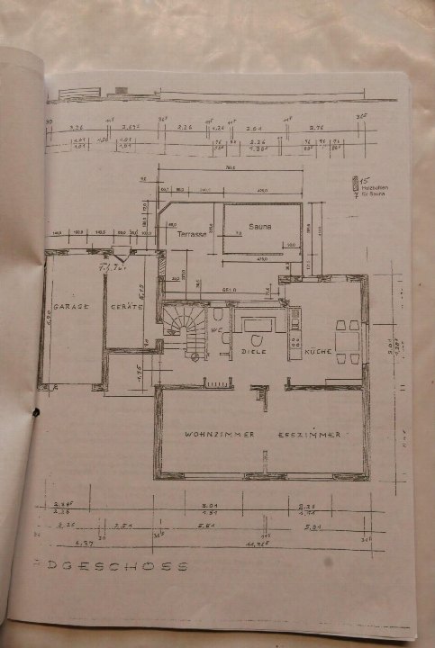 Grundriss des Erdgeschosses eines Einfamilienhauses mit Wohnzimmer, Esszimmer, Küche, Diele, WC, Sauna, Terrasse und Garage