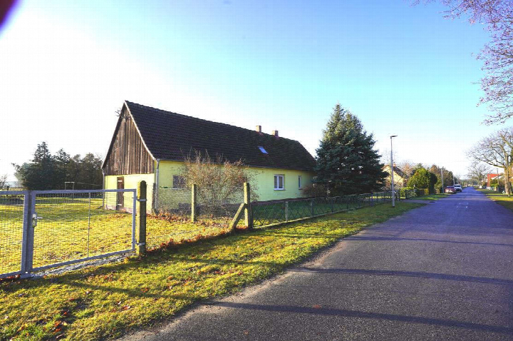 Einfamilienhaus mit gelber Fassade und dunklem Satteldach, Seitenansicht mit Garten und Zaun, Waldower Straße 7, Märkische Heide OT Klein Leine