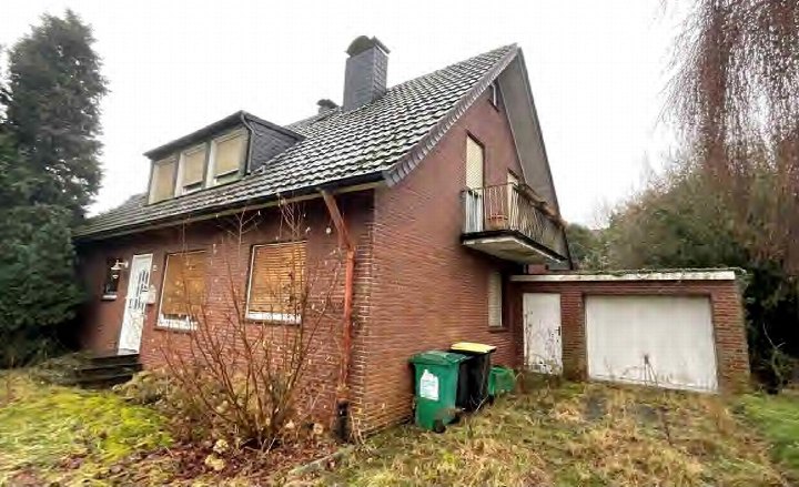 Seitenansicht eines Einfamilienhauses aus rotem Backstein mit Satteldach, Balkon, Garage und Garten in Rheurdt, Bergstraße 22