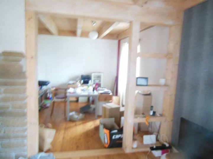 Innenraum mit Holzkonstruktion, Arbeitstisch und verschiedenen Gegenständen, möglicherweise ein Nebenraum oder Lagerbereich