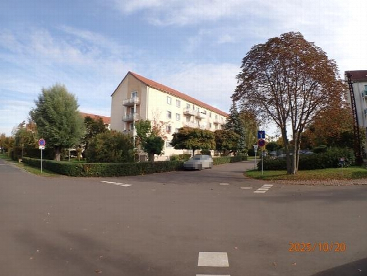 Vorderansicht eines mehrstöckigen Wohngebäudes mit Balkonen, rotem Dach und umgebenden Bäumen und Hecken in Bad Dürrenberg