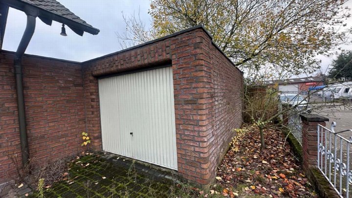 Brickgarage mit weißer Rolltür, umgeben von Laub und Mauer, Am Schornacker 28 A, Wesel