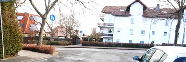 Außenansicht eines weißen Mehrfamilienhauses mit braunem Ziegeldach an der Dürerstraße in Neu-Anspach, umgeben von Bäumen und einer Straße