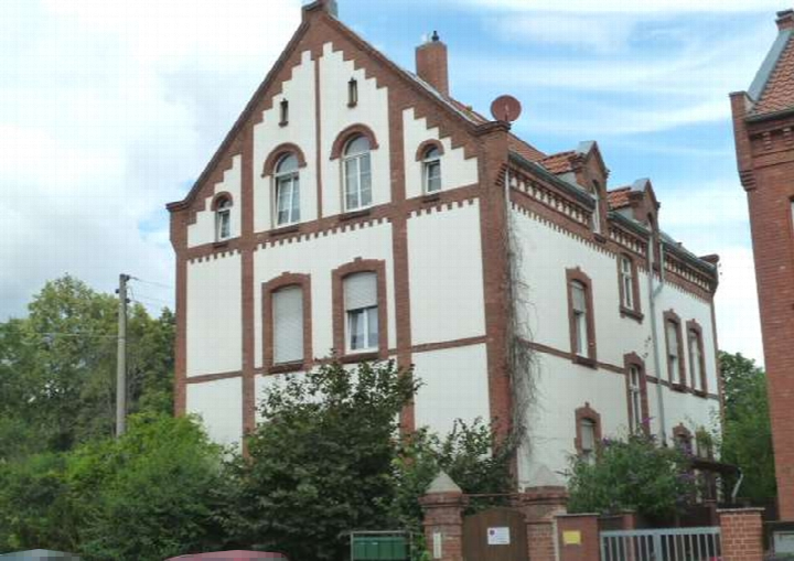 Seitenansicht eines mehrstöckigen Gebäudes mit weißer Fassade und roten Ziegeln, Halberstädter Straße 32, Quedlinburg