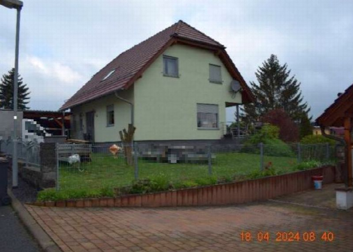 Einfamilienhaus mit hellgrüner Fassade und Satteldach, Vorgarten mit Zaun, Ansicht von vorne, Nessetal, Vor dem Berge 60