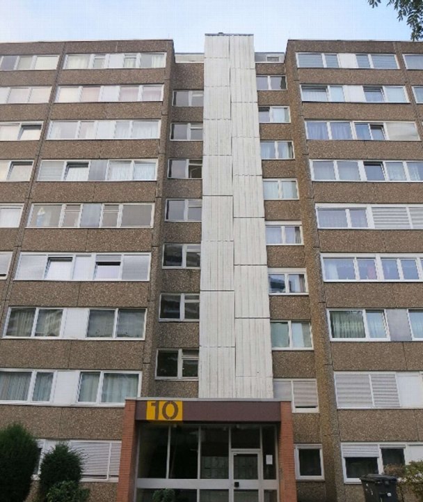 Vorderansicht eines mehrstöckigen Wohnhauses mit braunem Putz, weißen Fenstern und Eingang mit der Hausnummer 10