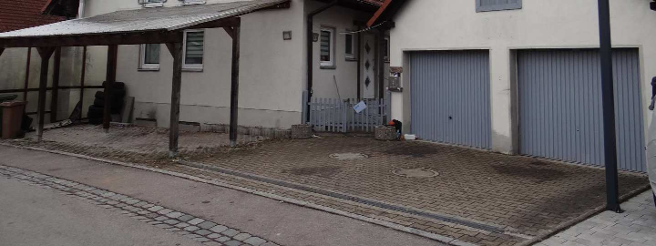 Außenansicht einer Garage mit zwei Rolltoren, gepflastertem Vorplatz und Holzüberdachung in Ansbach, Seligerstraße 9