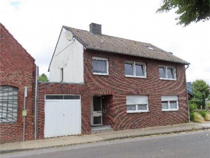 Einfamilienhaus in Titz, Bachstraße 18, mit rotem Backsteinfassade, Eingangstür, Garagentor und Dach mit Satellitenschüssel