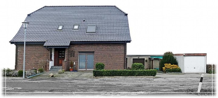 Einfamilienhaus mit Satteldach und Ziegelwand, Eingangsbereich mit Treppe, Nebengebäude und Garage im Vordergrund