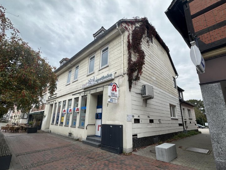 Einfamilienhaus mit Ladenlokal an der Ecke Steinweg 7 in Gifhorn, weiß verputzt, mit Apotheken-Schild und Rankpflanzen am Dachfirst