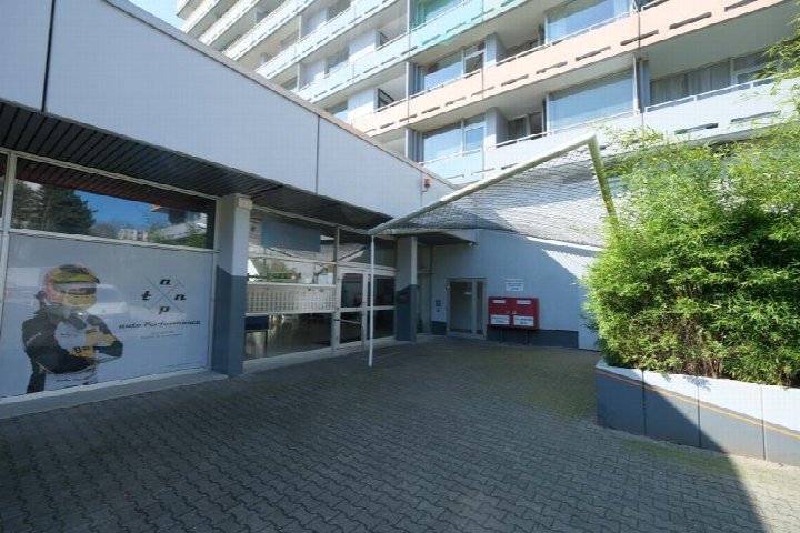 Eingangsbereich eines Mehrfamilienhauses mit Glasfront, Überdachung und Pflanzen im Vorgarten in Eschborn, Bremer Straße 17–33