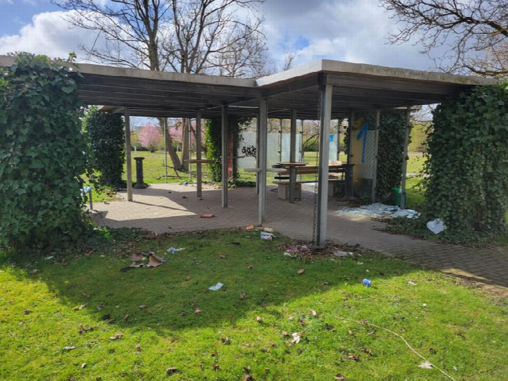 Gartenbereich mit überdachter Sitzgelegenheit, Efeu bewachsenen Pfeilern und Grünfläche, leicht verschmutzt, im Außenbereich des Grundstücks Riemekestraße 160 in Paderborn