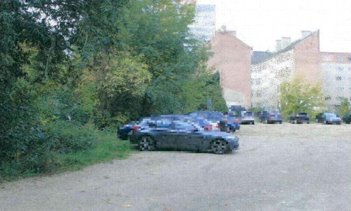 Parkplatz mit mehreren Fahrzeugen vor Gebäuden und Bäumen in Frankfurt (Oder), Schulstraße