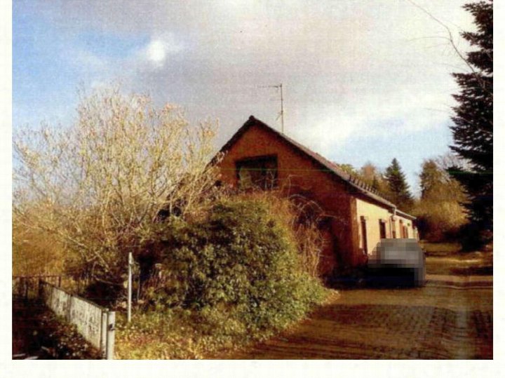 Einfamilienhaus mit Satteldach und Vorgarten, Ansicht von vorne, umgeben von Bäumen und Sträuchern