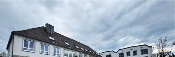 Seitenansicht eines Gebäudes mit Satteldach und Dachfenstern in Mindelheim, Reinpoldstr. 5/5a unter bewölktem Himmel