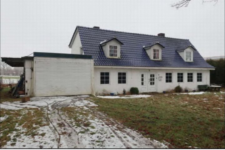 Einfamilienhaus mit blauem Ziegeldach und weißen Fassaden, Vorderansicht mit Garage und schneebedecktem Vorgarten in Schackendorf, Wierensiek 1