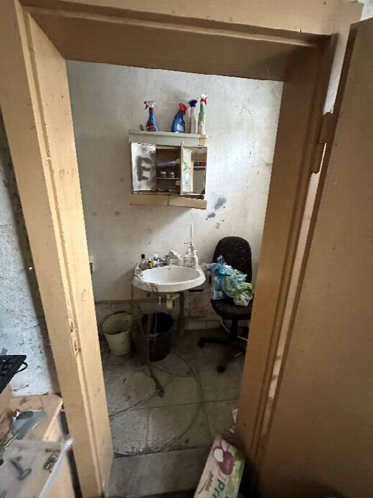 Blick in ein Badezimmer mit Waschbecken, Wandschrank und Stuhl
