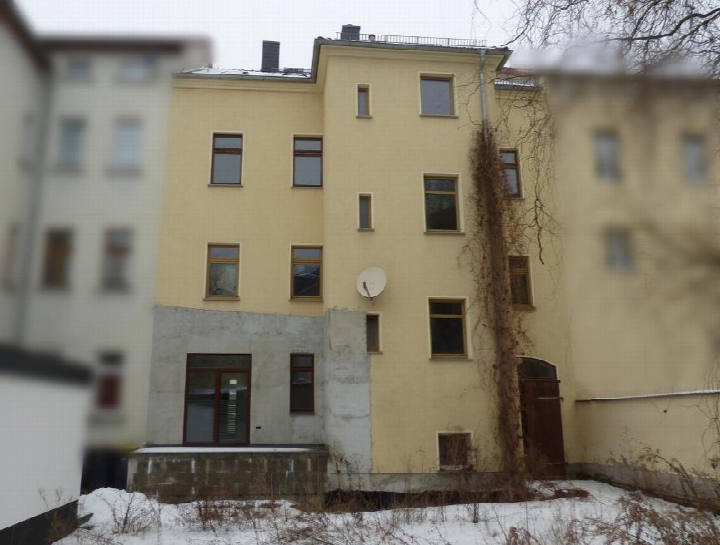 Rückansicht eines mehrstöckigen Gebäudes in Borna, Bahnhofstraße 27, mit Fenstern, Satellitenschüssel und schneebedecktem Boden