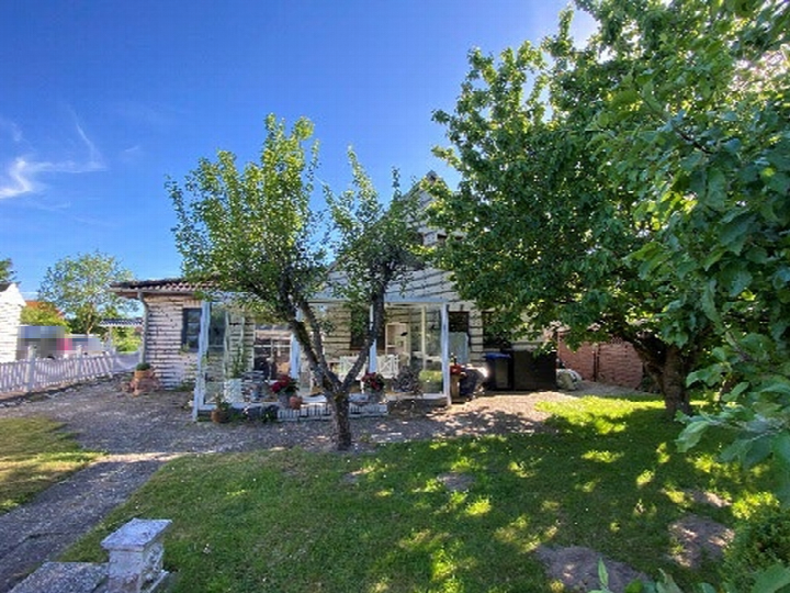 Haus mit Vorgarten, Laubengang und Bäumen unter blauem Himmel