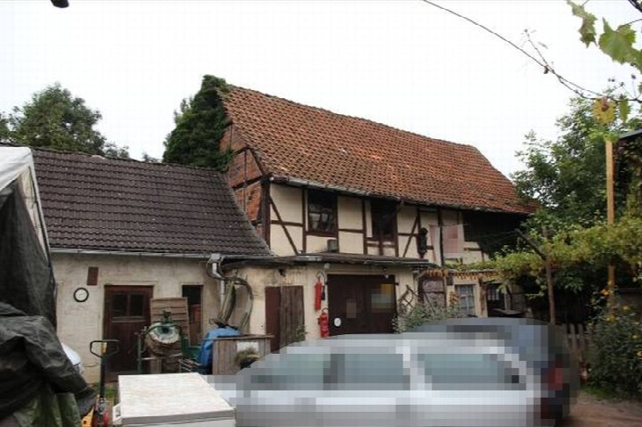 Vorderansicht eines Fachwerkhauses mit Ziegeldach, Eingangstür und angrenzenden Gebäudeteilen sowie Gartenbereich in Gernrode, Marktstraße 7
