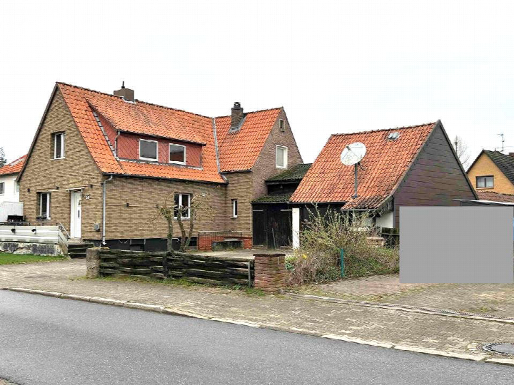 Einfamilienhaus mit rotem Ziegeldach und Backsteinfassade, Eingangsbereich mit Stufen, Vorgarten und Holzzaun, Ansicht von der Straße aus, Altenmedingen, Am Windmühlenberg 4