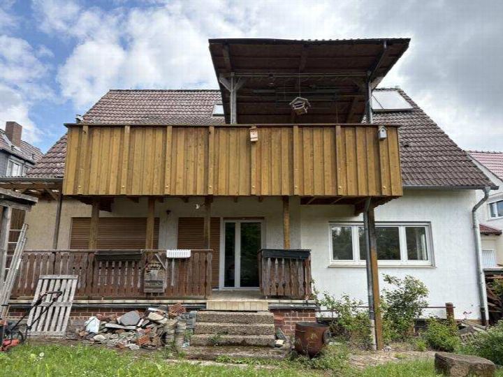 Vorderansicht eines Einfamilienhauses mit Holzbalkon, Eingangstür und Vorgarten in Felsberg, Vorderbinge 11