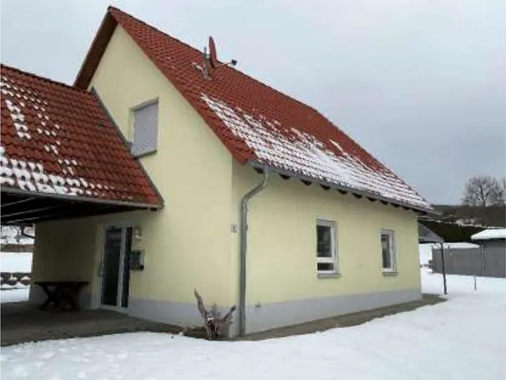 Seitenansicht eines gelben Gebäudes mit rotem Ziegeldach und Schneebedeckung im Winter, Erlenweg 6, Nordheim v. d. Rhön