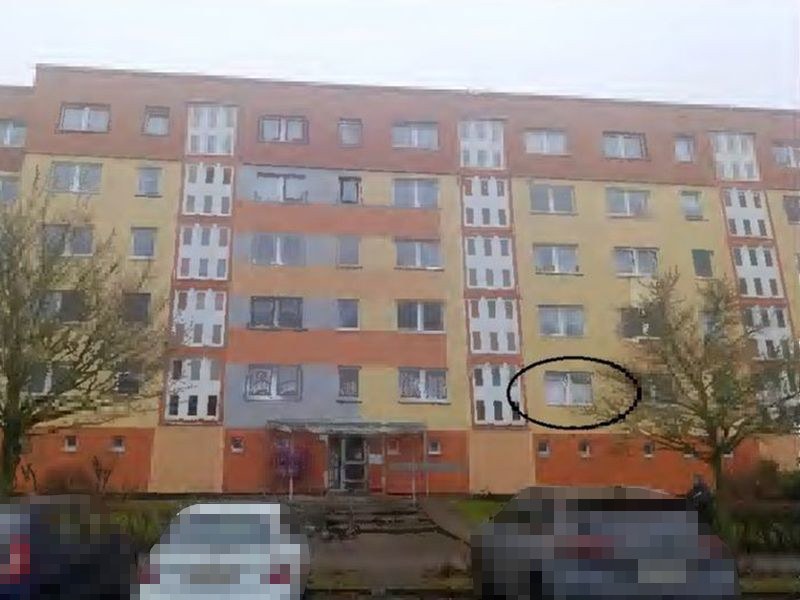 Fassade eines mehrstöckigen Wohnhauses in Greifswald, Ernst-Thälmann-Ring 63b, mit farblich gestalteten Fassadenteilen und markiertem Fenster im Erdgeschossbereich