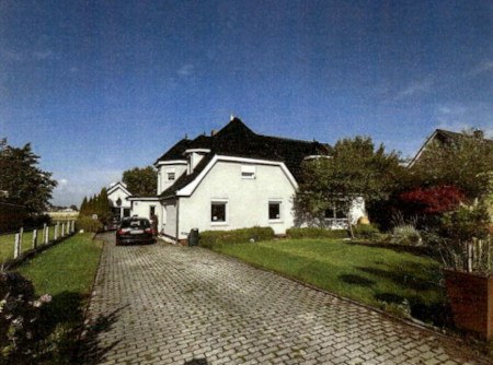 Einfamilienhaus mit dunklem Dach und weißer Fassade, gepflasterter Einfahrt, grüner Vorgarten, geparktem Auto, Simonsberg, Rieke Reech 61
