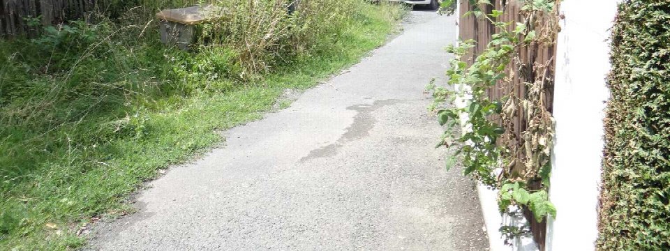 Pflasterweg im Gartenbereich mit Grünflächen links, weißer Mauer mit Rankpflanzen rechts, Schleusenweg 19, Wallenfels