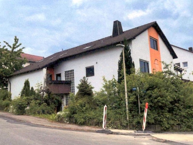 Zweistöckiges weißes Gebäude mit orangefarbener Fassadenecke, dunklem Dach und Fenstern, umgeben von Grünanlagen, in Burgstetten-Burgstall, 71576, Wohnfläche EG ca. 122