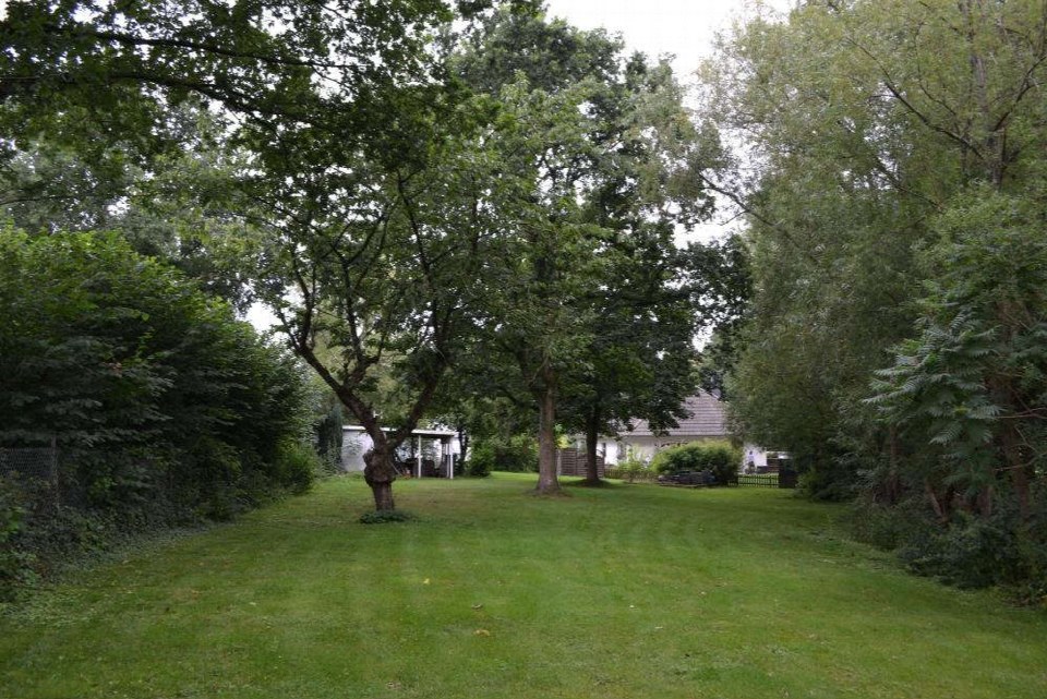 Grüner Garten mit Bäumen und Sträuchern, im Hintergrund ein Wohnhaus in Pohnsdorf, Seestraße 3, 5