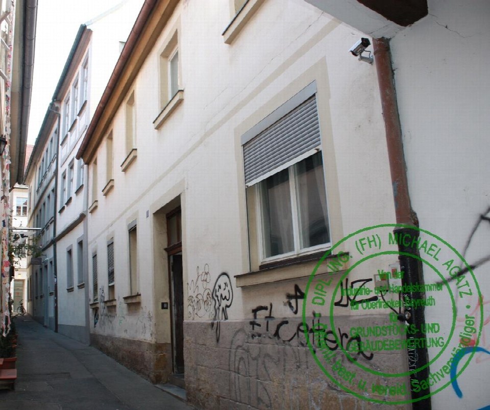 Seitenansicht eines mehrstöckigen Gebäudes in der Hasengasse 1, Bamberg, mit Fenstern, Tür, Steinsockel und Graffiti an der Fassade