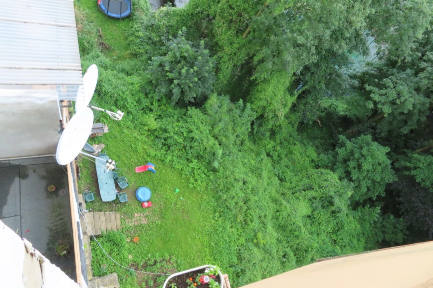 Überblick über einen grünen Gartenbereich mit Spielgeräten, Satellitenschüsseln und Bäumen neben einem Gebäude in Wuppertal