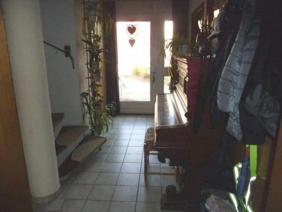 Eingangsbereich eines Reihenhauses mit Fliesenboden, Glastür, Pflanzen und einem Flügel. Eichendorffstraße 48, Ibbenbüren