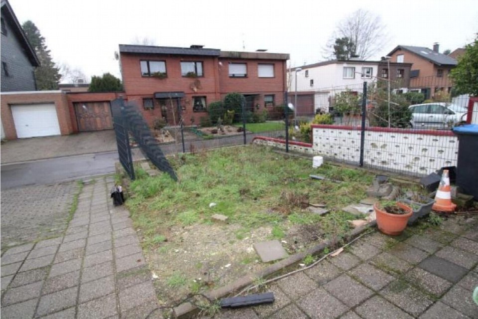 Überwucherter Gartenbereich mit Gras, Unkraut, Müll und einem Blumentopf vor einem Einfamilienhaus in Marl, Käthe-Kollwitz-Straße 20