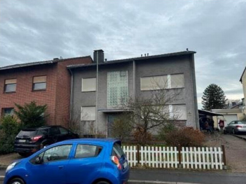 Außenansicht vorne eines Zweifamilienhauses in Lünen, Lilienweg 22, mit grauer und roter Fassade, Fenstern, Eingang und weißem Zaun im Vorgarten