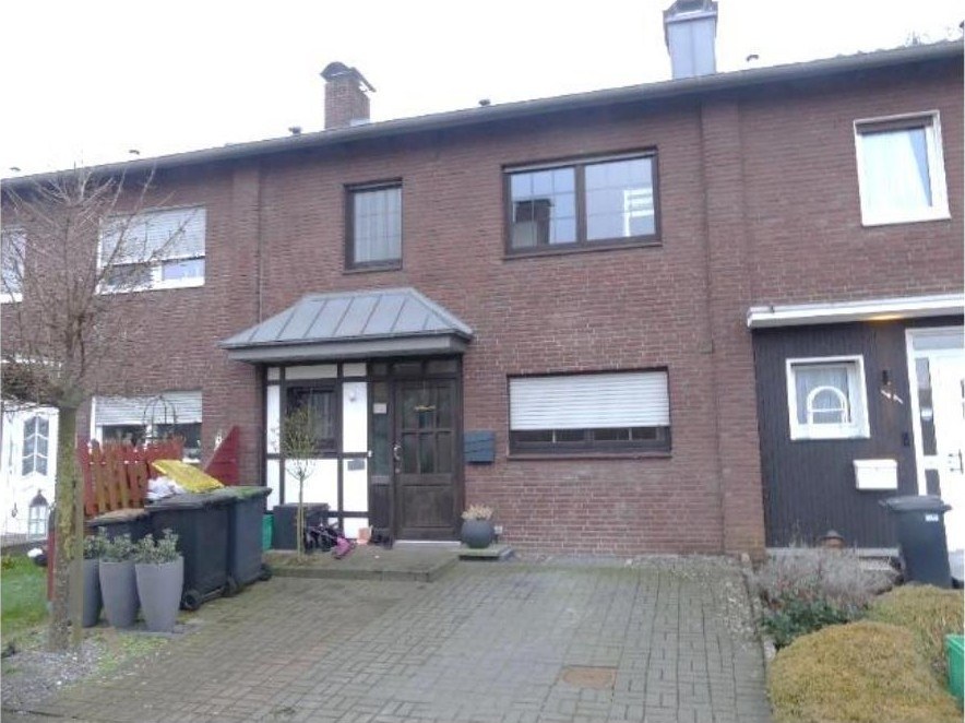 Vorderansicht eines zweistöckigen Backstein-Einfamilienhauses mit Eingang, Fenstern und Vorgarten