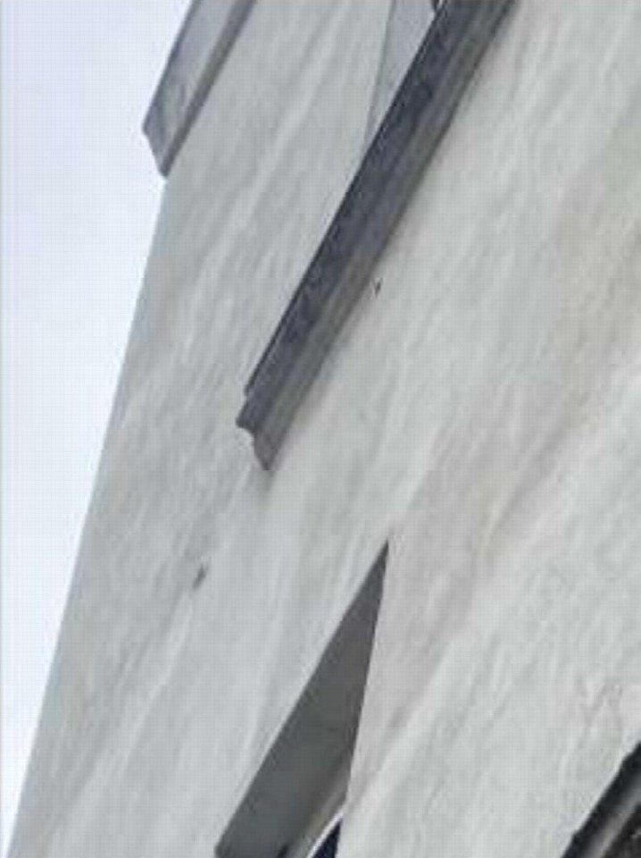 Außenansicht der Seitenfassade eines Gebäudes mit sichtbaren Fensterelementen und strukturiertem Putz