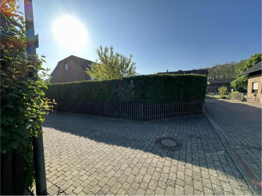 Pflasterweg mit Hecke und Holzzaun, im Hintergrund Gebäude und Bäume, Gartenbereich einer Doppelhaushälfte in Köln