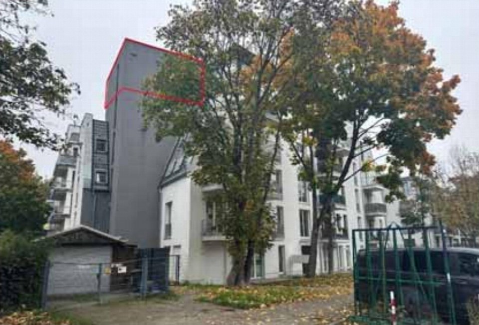 Seitenansicht eines Mehrfamilienhauses in Berlin, Einbecker Straße 51, mit grauer Fassade und umgebenden Bäumen im Herbst