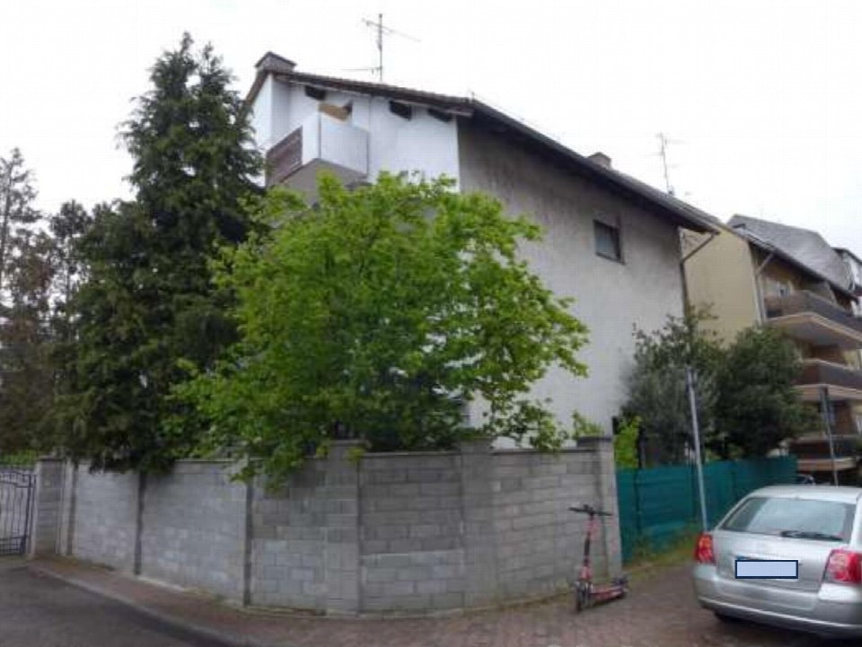Seitenansicht eines Mehrfamilienhauses mit Betonmauer, Bäumen und geparktem Auto in Frankfurt am Main, Griesheim, Buchenstraße 12
