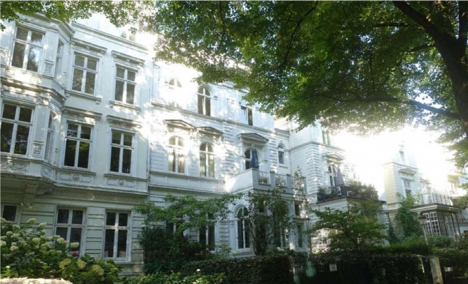 Fassade eines mehrstöckigen Wohnhauses in Hamburg-Rotherbaum mit Balkonen und Bäumen im Vordergrund