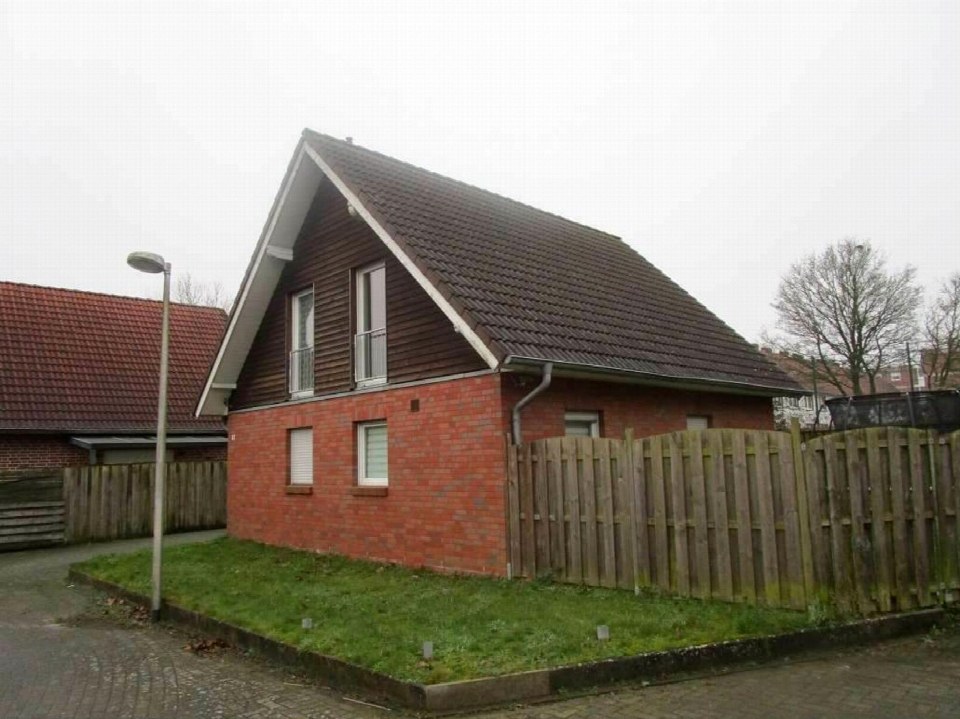 Seitenansicht eines Einfamilienhauses mit rotem Ziegelmauerwerk, braunem Satteldach und Holzzaun im Vorgarten, Königstraße 67, 48599 Gronau