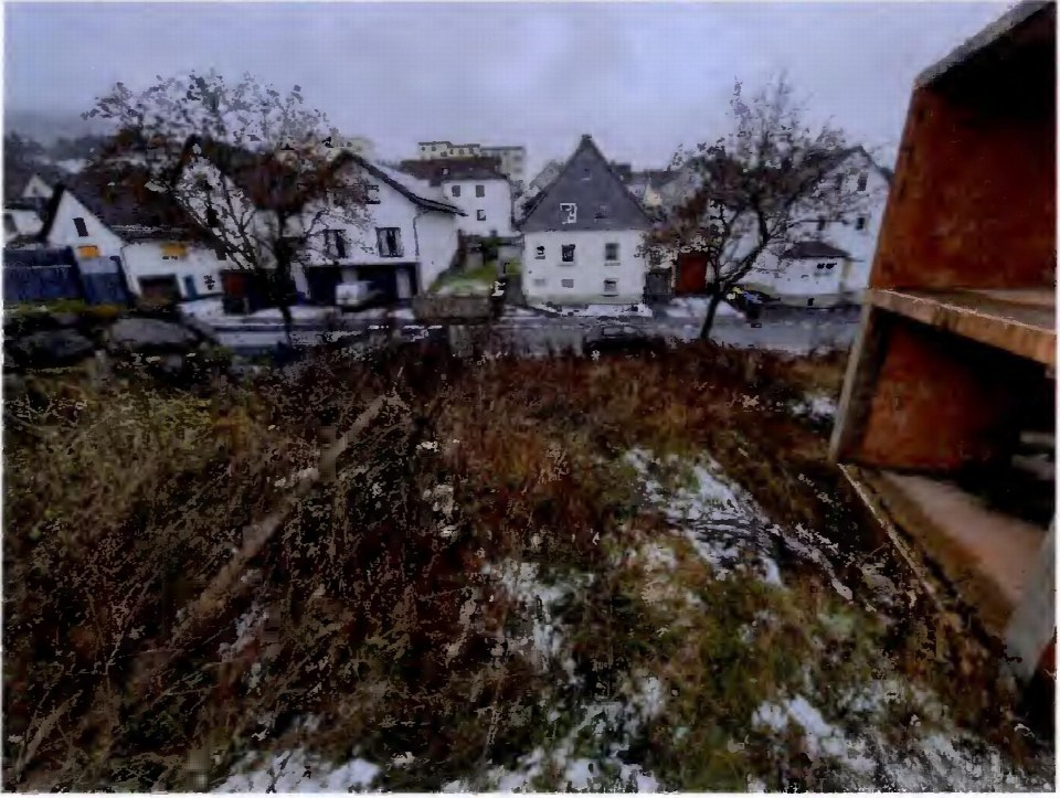 Überwuchertes Grundstück mit Schneeresten und Blick auf umliegende Gebäude in Breidenbach, Bachstraße 19