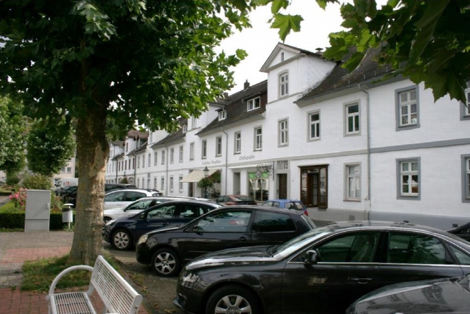Außenansicht der Friedrichstraße 8 in Karlshafen mit weißer Fassade, mehreren Fenstern und geparkten Autos vor dem Gebäude
